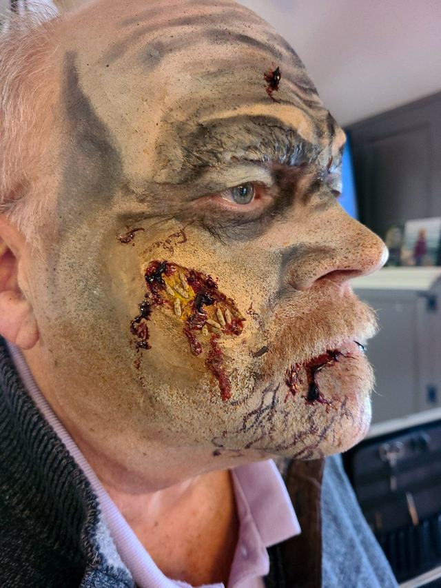 Grey, decaying old-man zombie with an open wound on the cheek
