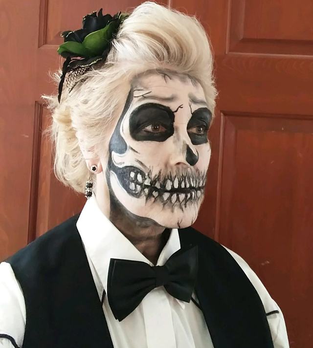 Skeleton face with a black bow tie and a rose in the hair