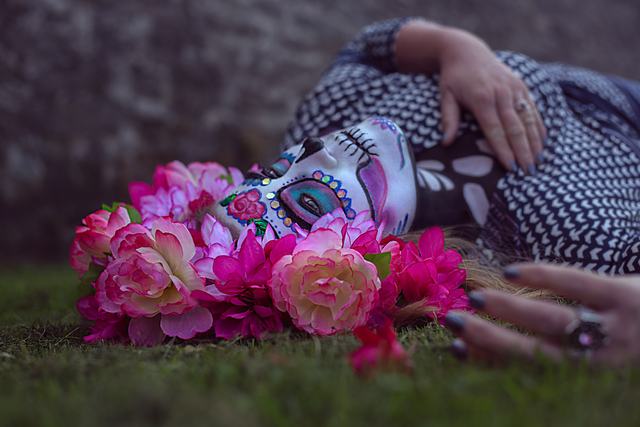 The floral sugar-skull look, model reclining in the grass among pink flowers