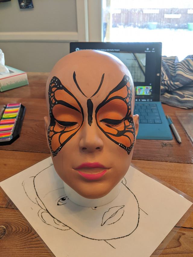 Monarch-butterfly mask painted on a practice head