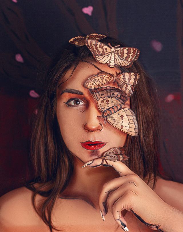 Moths painted across one eye and the hand of a dark-haired model