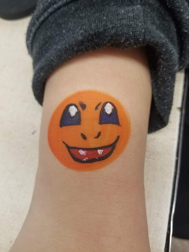 Orange fanged critter painted on a forearm