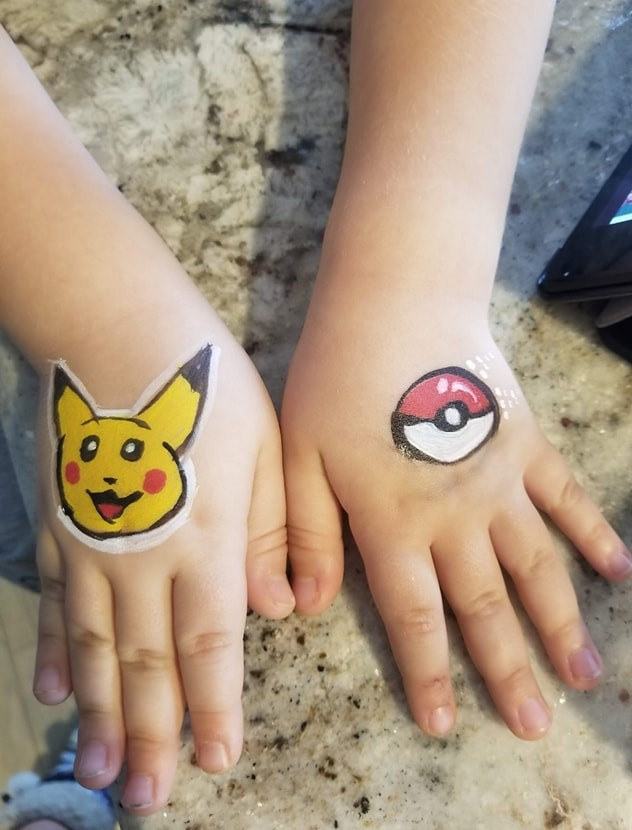 Pikachu and a Poké Ball painted on two hands