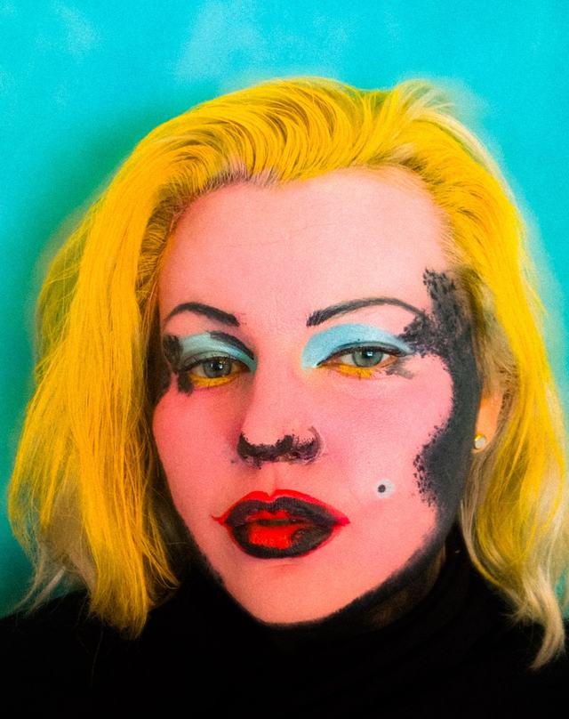 Pop-art face in saturated pink and yellow, with one textured black cheek