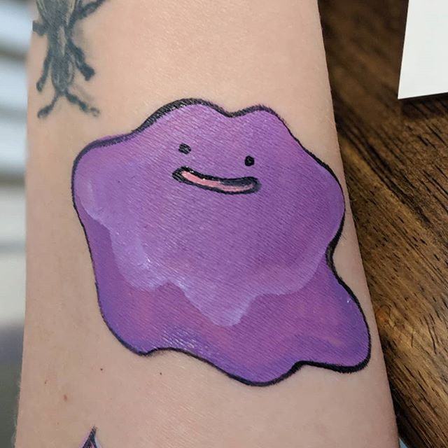 Smiling purple blob painted on a forearm