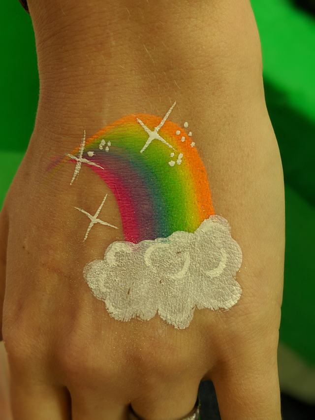 Rainbow arcing out of a glittering cloud on the back of a hand