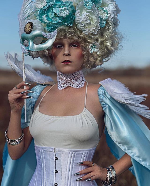 Snow Queen: white-haired model in a corset and feathered cape