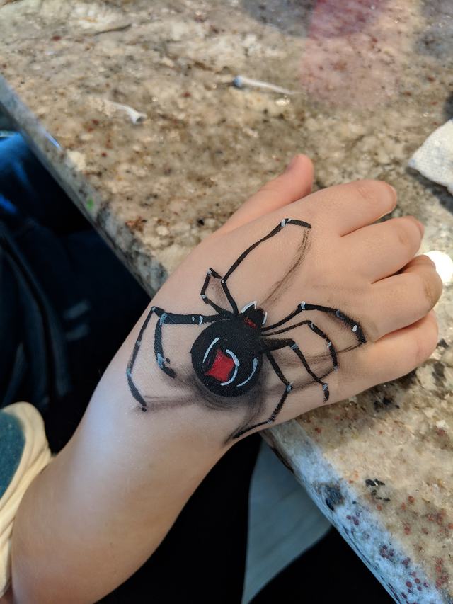 Black spider painted on the back of a hand