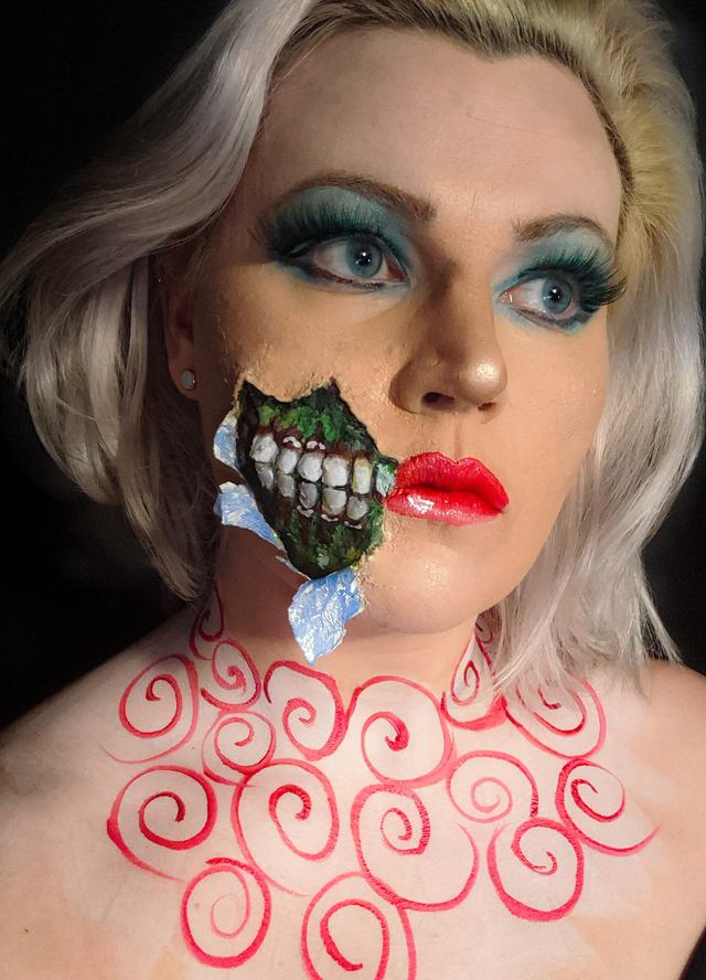 Torn-cheek effect revealing teeth, with red swirls painted on the neck