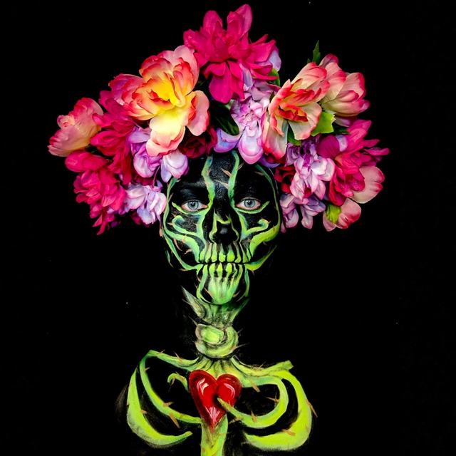 Neon-green skeleton face and ribcage with a red heart, under a flower crown, on black
