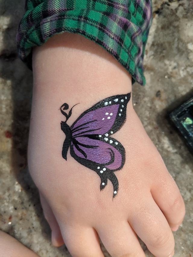 Violet butterfly painted on the back of a hand