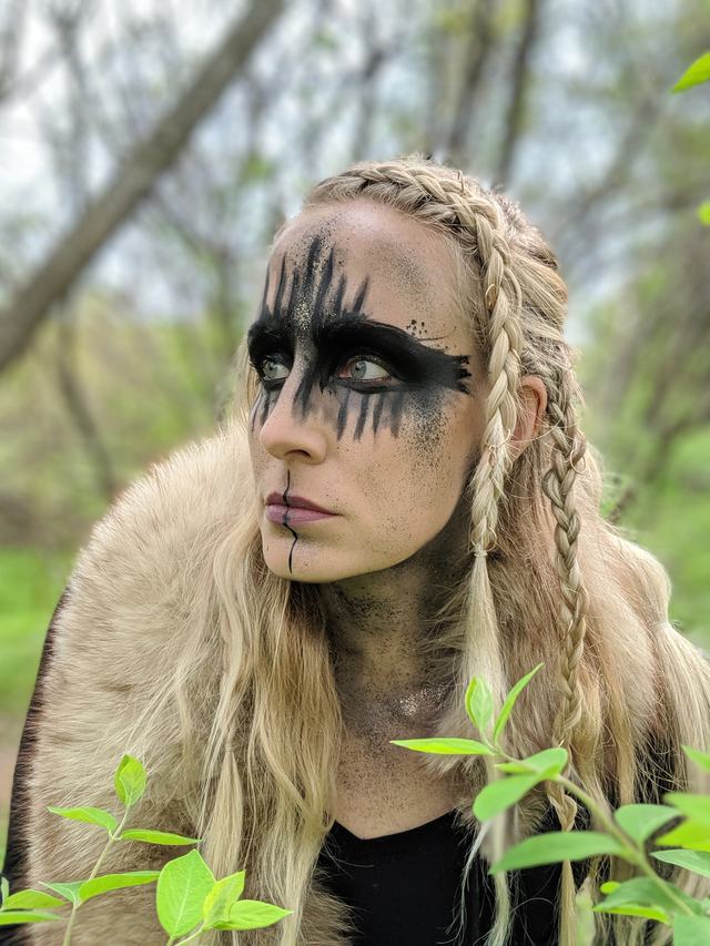Warrior look: black war paint across the eyes, braided hair and a fur collar, outdoors